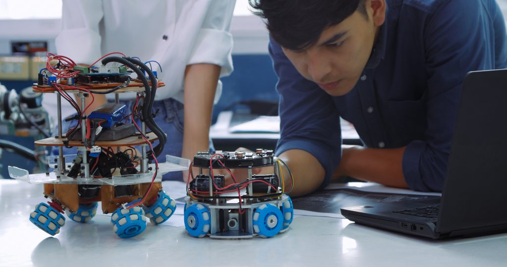 Engineering students engage in a collaborative effort to program and test robots using AI in a bright modern laboratory setting,