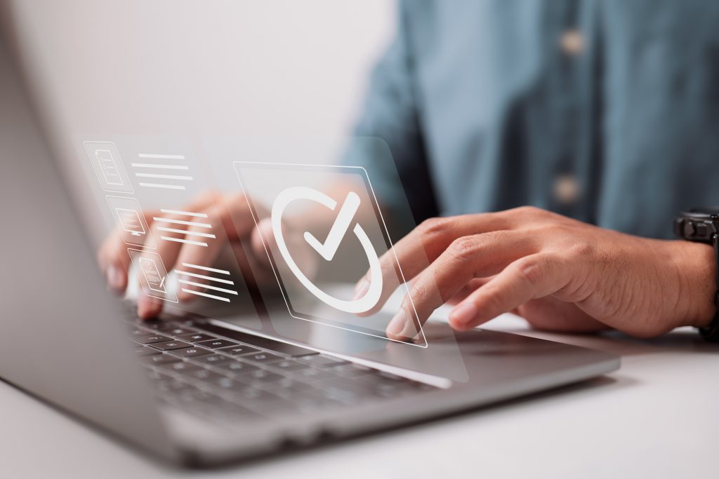 Closeup of hands on a laptop and a large tick or check mark is digitally imposed over the image.